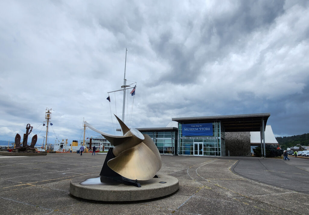 exterior of the Columbia River Maritime Museum with a ship's propeller in the foreground