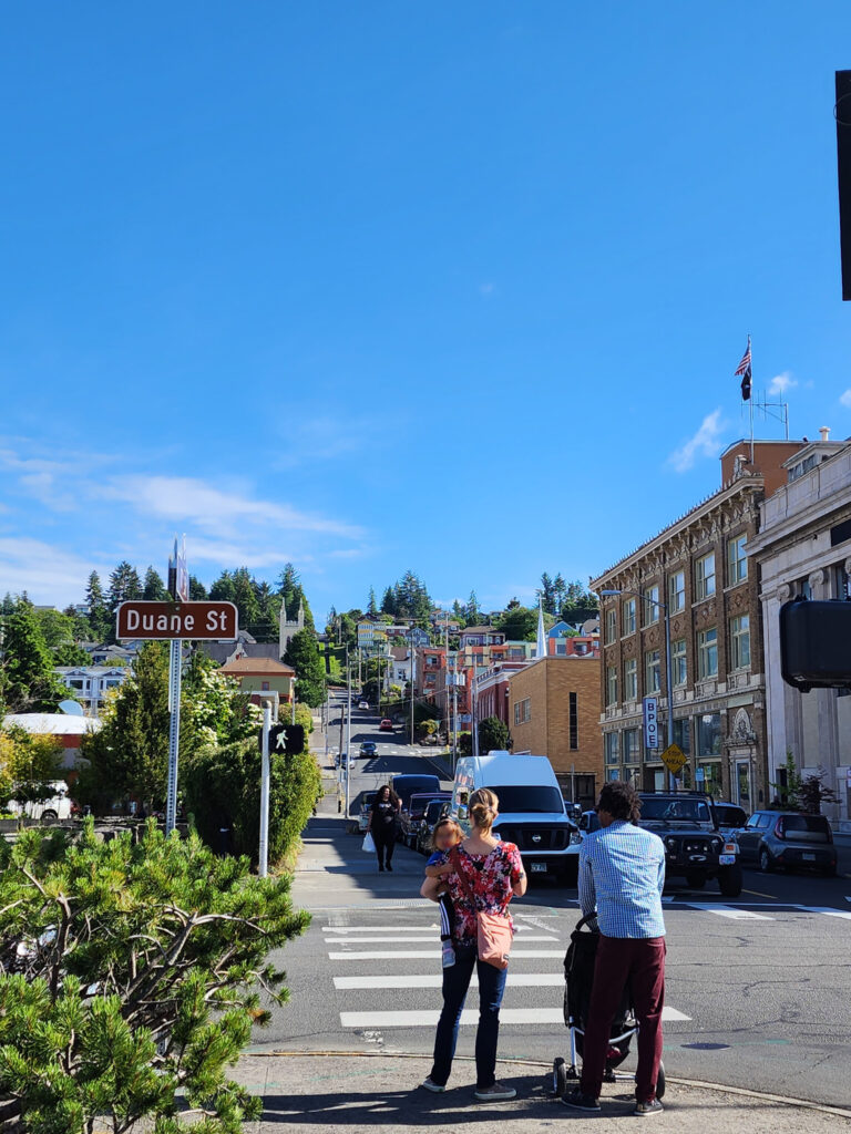 a family waits to cross a street on a sunny day in Astoria, Oregon