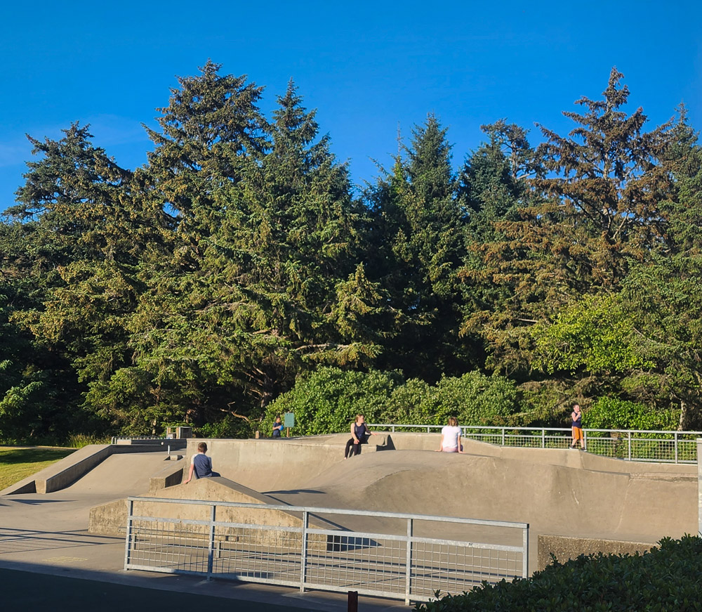 boys and their mothers hanging out at the skate park on a sunny day in Cannon Beach, Oregon