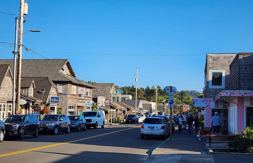 looking down the main street of shops and tourists on a cloudless day in Cannon Beach, Oregon.