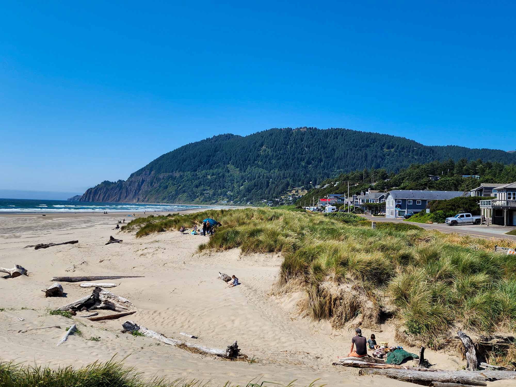 a beachfront at the Pacific Ocean with families picnicking on a sunny day in Manzanita, Oregon.