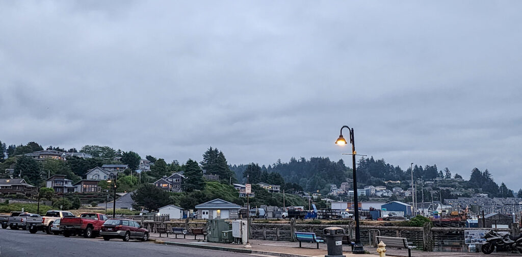 photo of a street scene and hillside neighborhood in Newport, Oregon at dusk