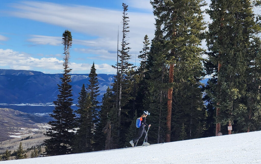 A woman skiing uphill to Elk Camp at Snowmass.
