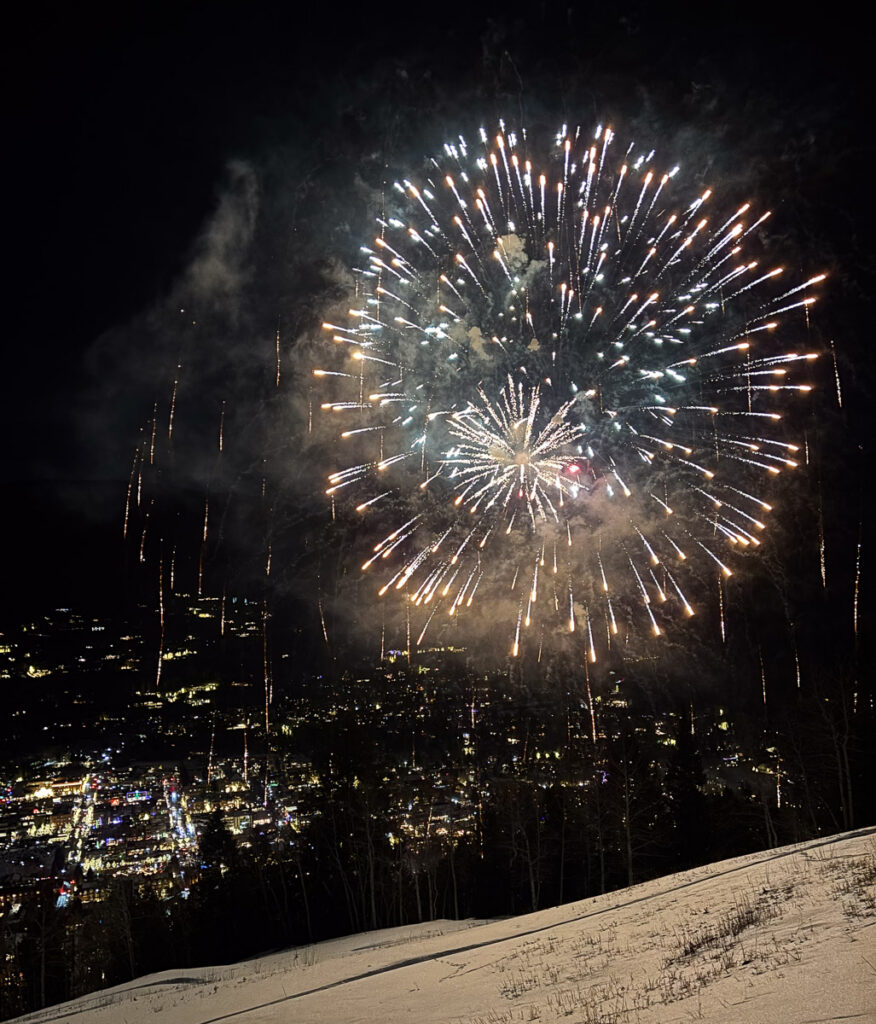 fireworks over the mountainside and city lights below in Aspen, CO